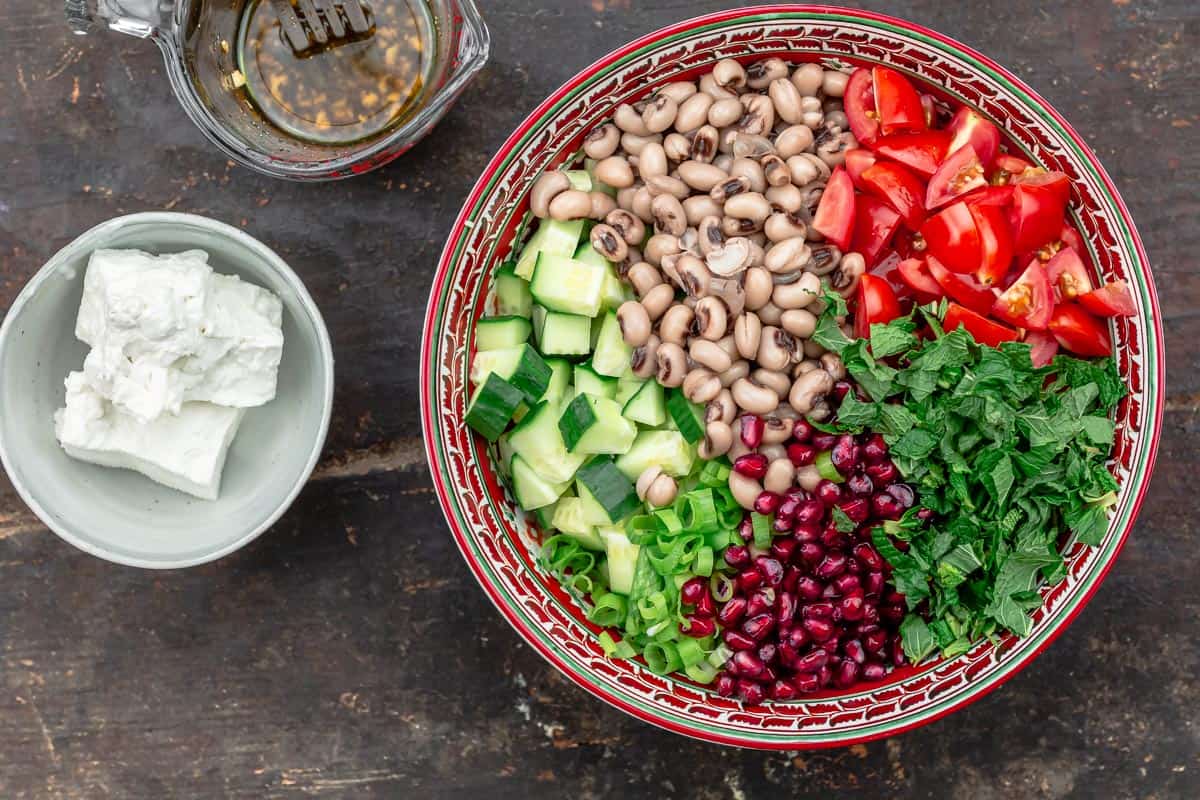 black eyed pea salad in a bowl, feta cheese and dressing in separate bowls